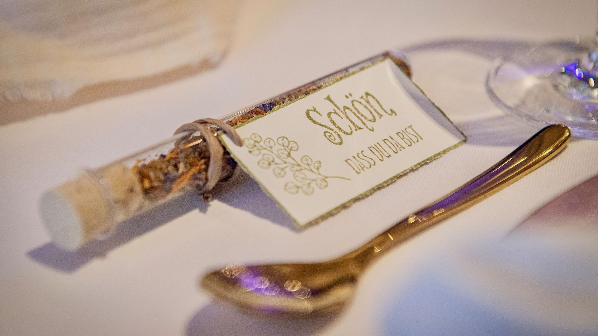 Gastgeschenk Hochzeit im Reagenzglas mit Papieranhänger Schön dass du da bist dekoriert auf einem Tisch mit Gold